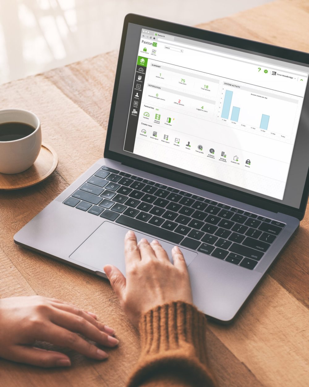 Mockup image of a woman's hand using and touching on laptop touchpad with blank white desktop screen with coffee cup on wooden table
